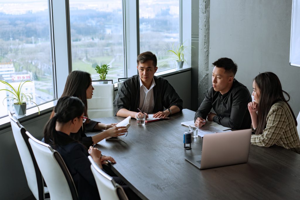 Team of Asian colleagues in a boardroom meeting, discussing documents and a laptop